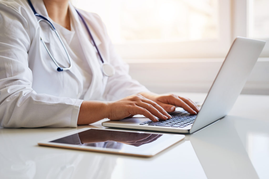 Female doctor typing on her laptop computer in medical office